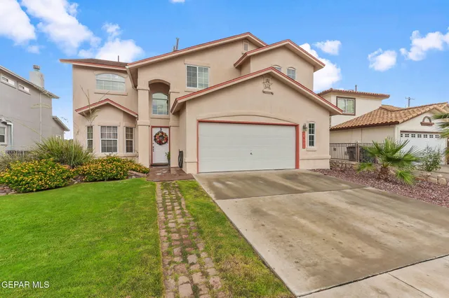 a view of a white house next to a yard with potted plants