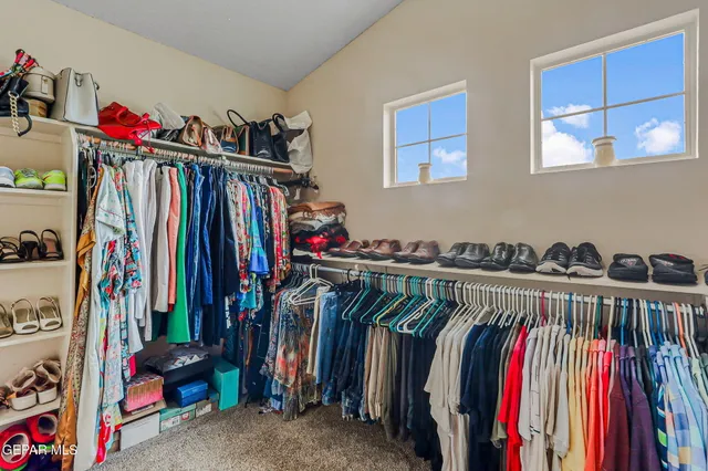 a view of walk in closet with clothes and shoes