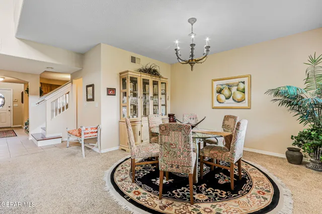 a dining room with wooden floor a chandelier a glass table and chairs
