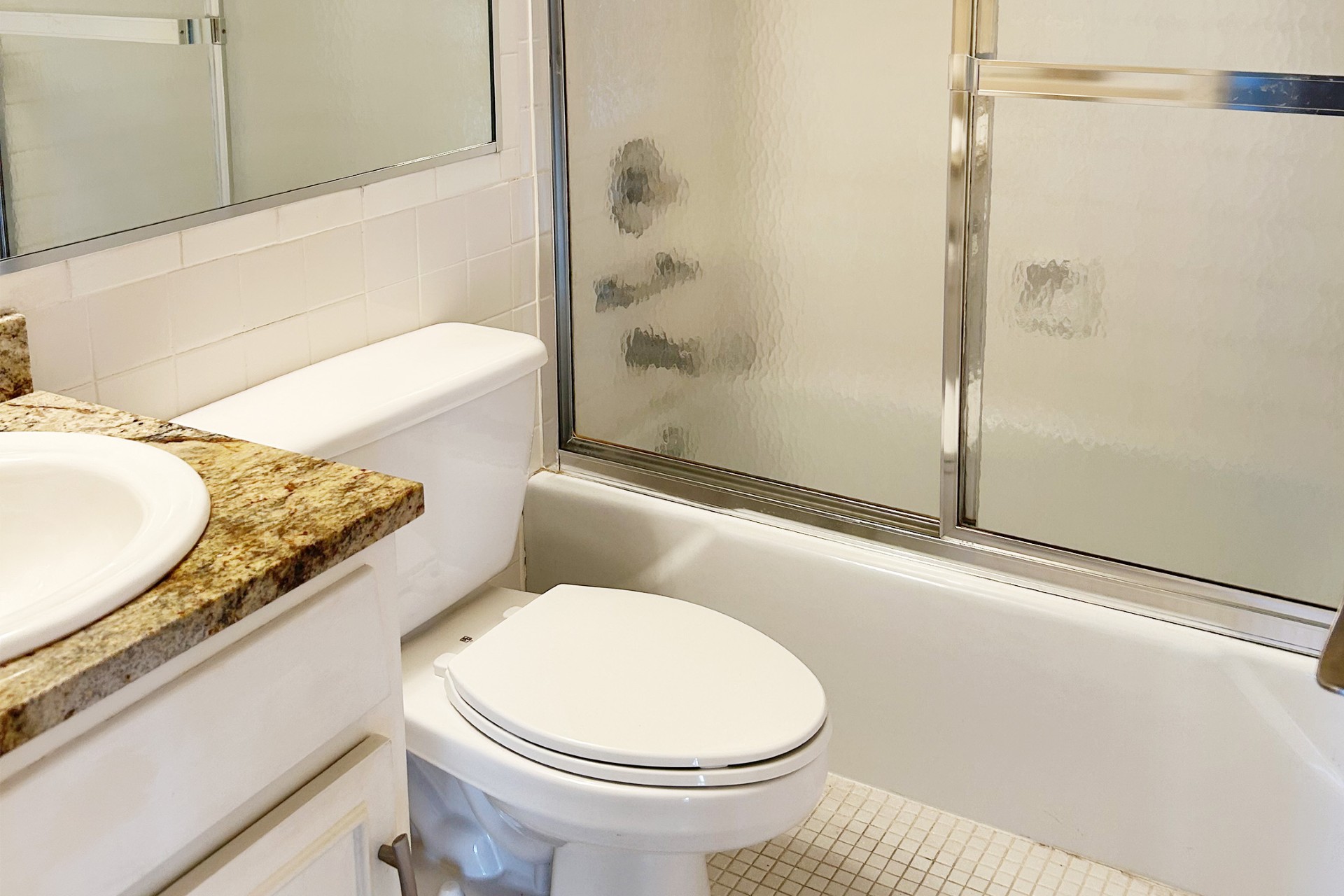 1122 Colorado Street, Unit 1101 Austin, TX 78701 - Photo 5 of 17 a bathroom with a granite countertop bathtub sink vanity mirror and toilet