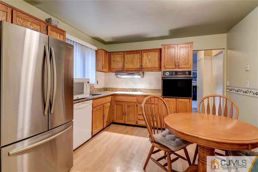 7 Arden Road Old Bridge, NJ 08857 - Photo 5 of 18 a kitchen with stainless steel appliances granite countertop a refrigerator a stove a sink dishwasher a dining table and chairs with wooden floor