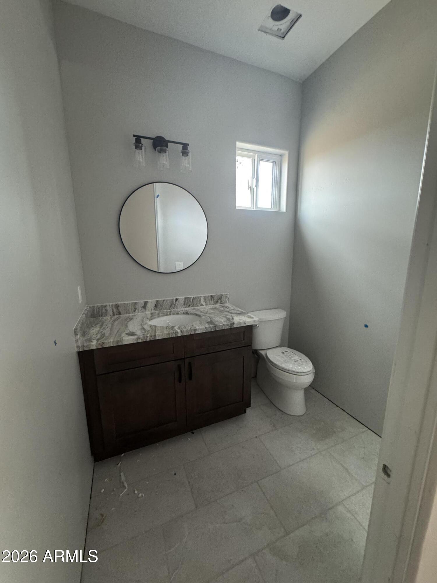 15728 West Montgomery Road Surprise, AZ 85387 - Photo 12 of 19 a bathroom with a granite countertop toilet a sink and mirror