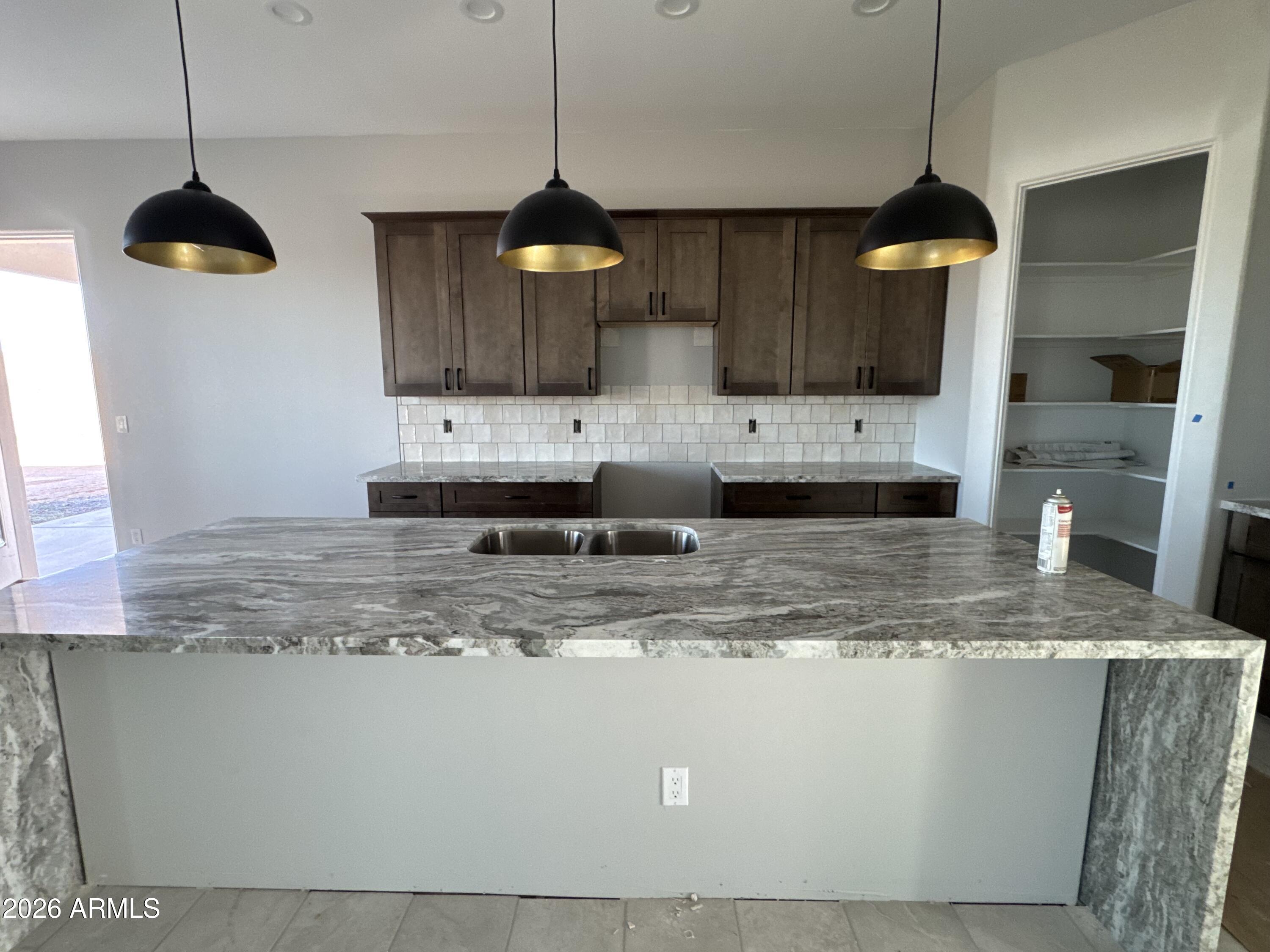 15728 West Montgomery Road Surprise, AZ 85387 - Photo 7 of 19 a kitchen with kitchen island granite countertop a sink a counter top space cabinets and stainless steel appliances