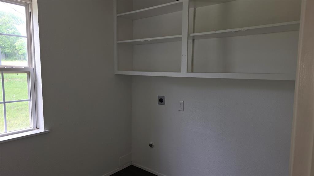 2474 Joe Davis Road Whitewright, TX 75491 - Photo 12 of 12 Utility space featuring built-in white shelving, a window with exterior views, and a dark wood-finish floor