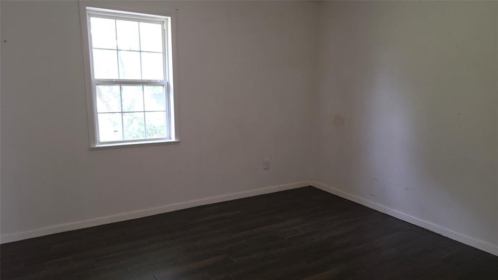 2474 Joe Davis Road Whitewright, TX 75491 - Photo 7 of 12 Bright interior space featuring a double-hung window, white trim, wood-finish flooring, and light-colored walls