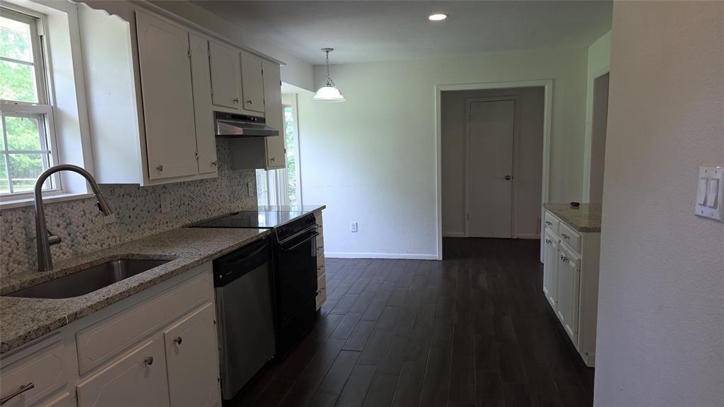 2474 Joe Davis Road Whitewright, TX 75491 - Photo 9 of 12 Renovated kitchen featuring granite countertops, stainless steel sink with gooseneck faucet, white cabinetry, integrated cooktop, and wood-finish flooring