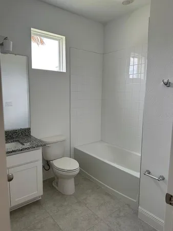 a bathroom with a granite countertop toilet a sink and a bathtub