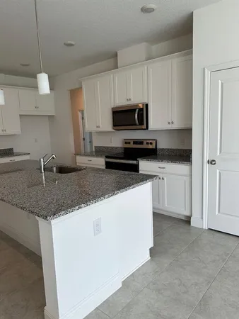 a kitchen with granite countertop a sink a counter space appliances and cabinets