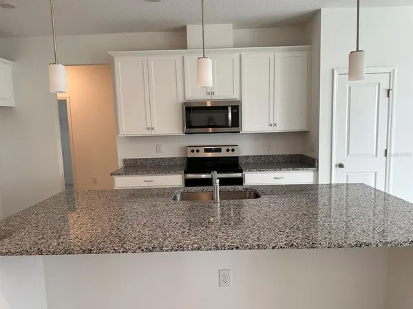 a kitchen with granite countertop a sink a stove and a refrigerator