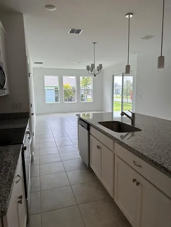 a large kitchen with granite countertop a sink a counter space and a stove