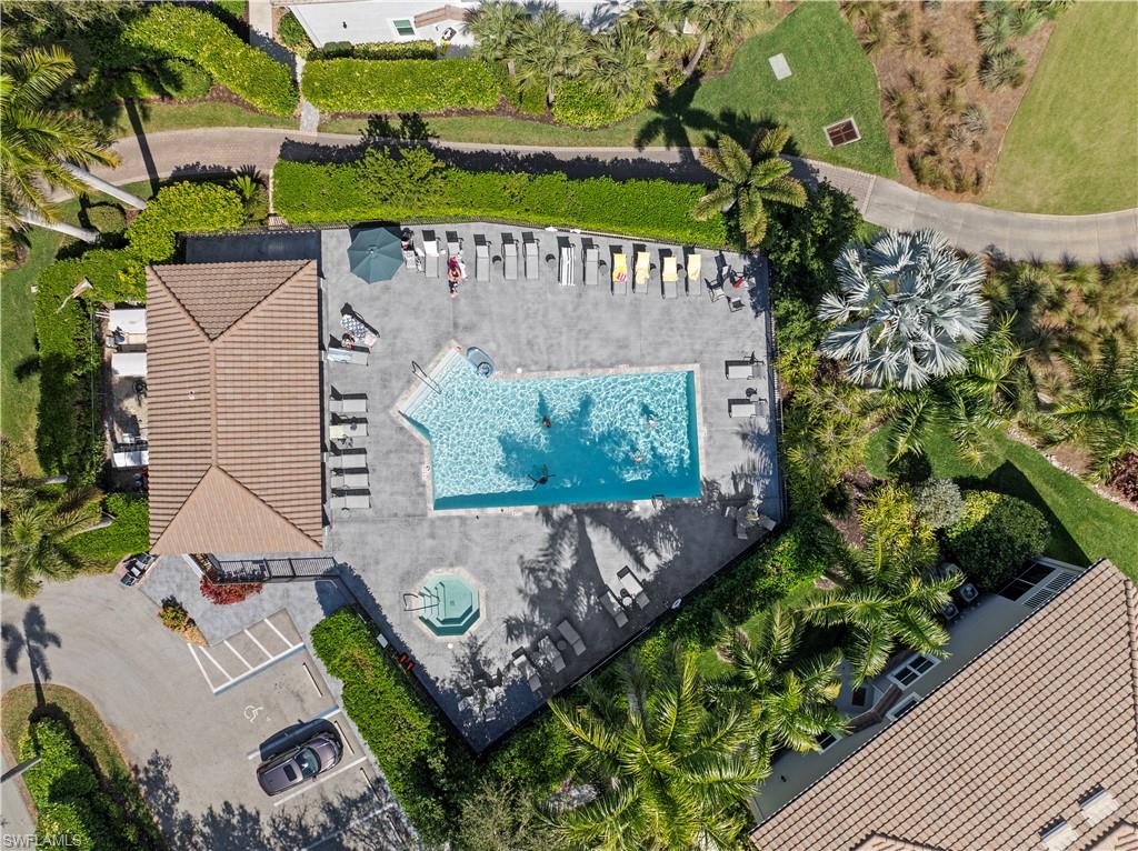 9331 Spring Run Boulevard, Unit 3005 Estero, FL 34135 - Photo 48 of 48 Community swimming pool with an integrated spa, expansive paver deck, adjacent clubhouse, and surrounding tropical landscaping