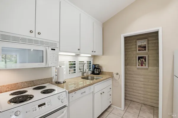 a kitchen with granite countertop white cabinets and white appliances