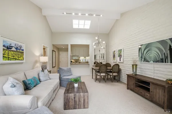 a living room with furniture a rug kitchen view and a chandelier