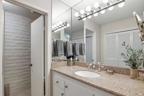 a bathroom with a granite countertop double vanity and a mirror