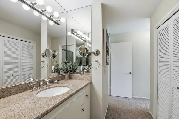 a bathroom with a granite countertop sink a mirror and shower