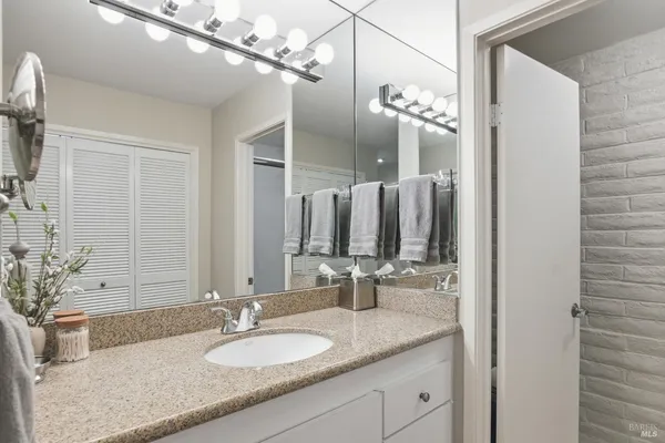 a bathroom with a granite countertop sink a large mirror and a shower