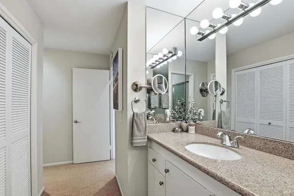 a bathroom with a granite countertop sink a mirror and a shower