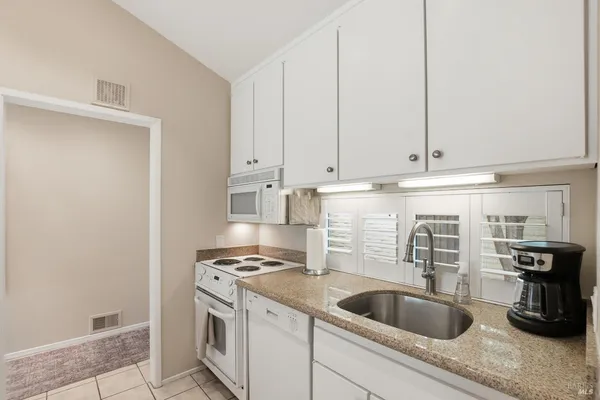 a kitchen with stainless steel appliances granite countertop a sink and a white cabinets