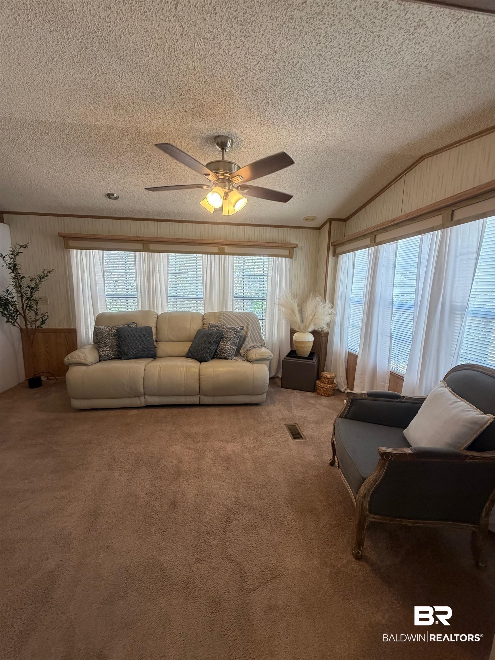 685 Escambia Loop Lillian, AL 36549 - Photo 7 of 43 Living room featuring wood walls, ceiling fan, carpet flooring, and a textured ceiling