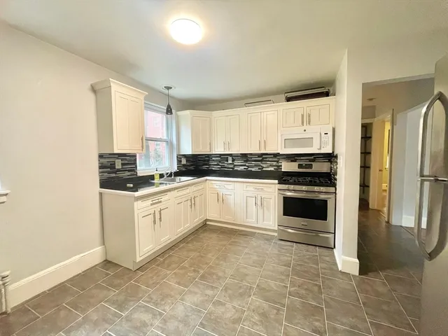 a kitchen with granite countertop a stove a sink and a refrigerator