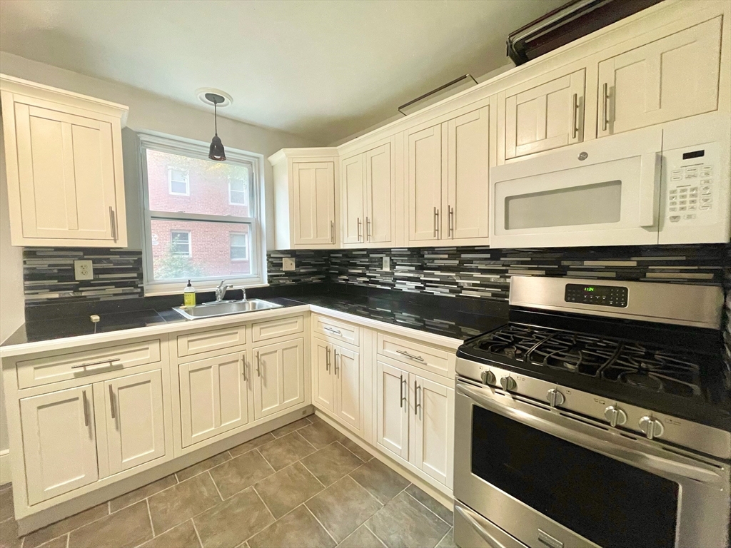 1 O'Leary Way, Unit 91 Boston, MA 02130 - Photo 6 of 12 a kitchen with white cabinets appliances and a window