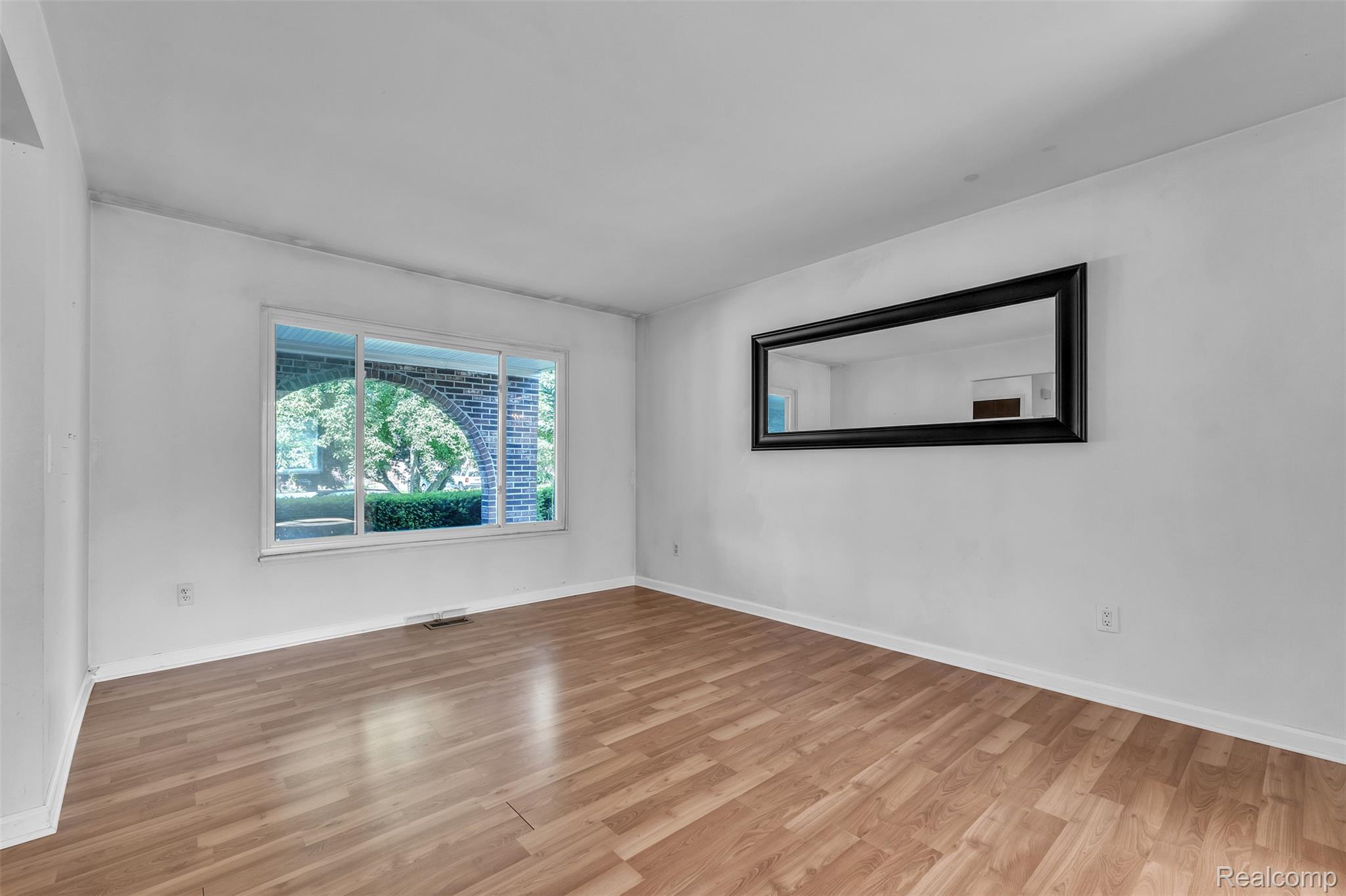 7000 Woonsocket Street Canton, MI 48187 - Photo 7 of 65 Sunlit room featuring wood-finish flooring, white walls, and a large picture window with a partial brick arch detail
