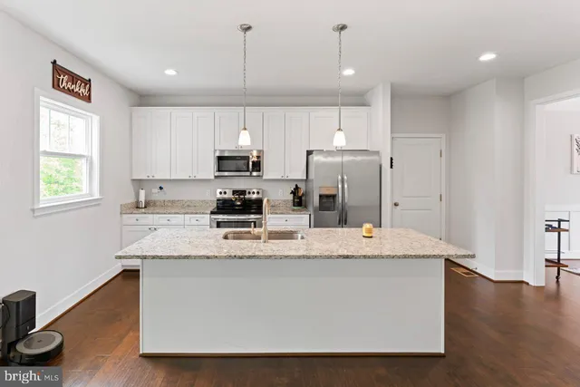 a kitchen with stainless steel appliances granite countertop a sink a stove a refrigerator cabinets and a window