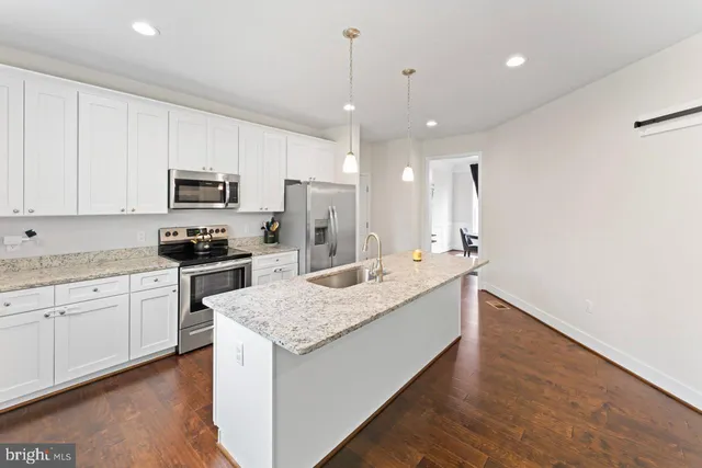 a kitchen with kitchen island granite countertop stainless steel appliances sink stove microwave and cabinets