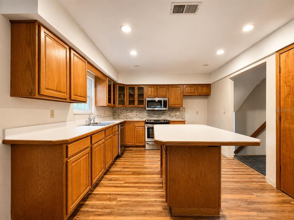 7119 Immokalee Road Keystone Heights, FL 32656 - Photo 14 of 50 a kitchen with stainless steel appliances kitchen island granite countertop a sink and wooden cabinets