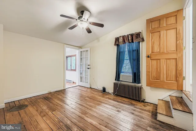 a view of an empty room with a window and wooden floor