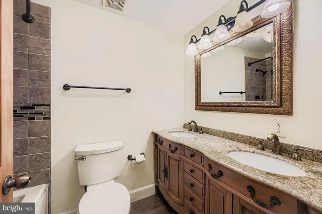 a bathroom with a granite countertop toilet sink and mirror