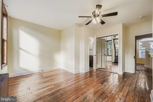 a view of empty room with wooden floor and fan