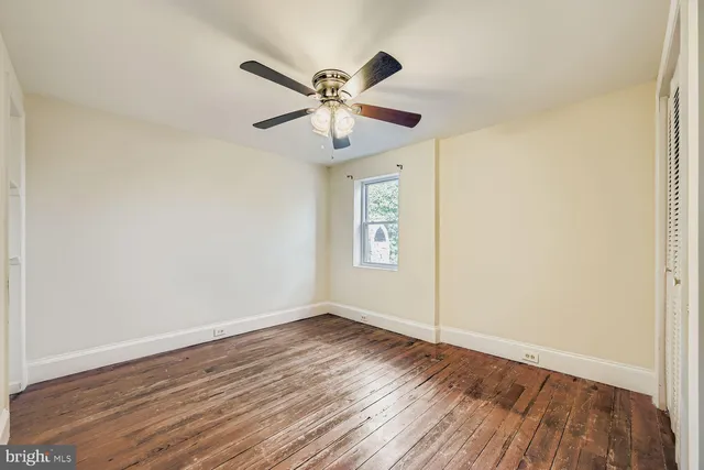 a view of empty room with wooden floor and fan