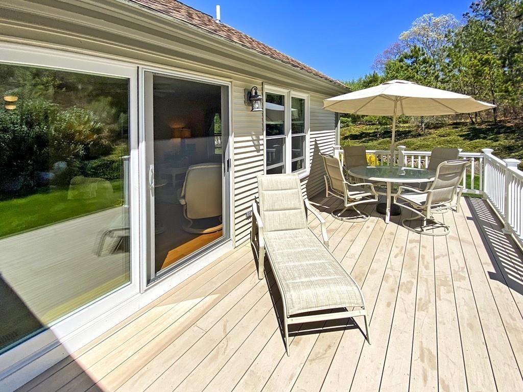 10 Weather Deck Road Bourne, MA 02532 - Photo 34 of 37 a view of a patio with a dining table and chairs under an umbrella with a barbeque grill