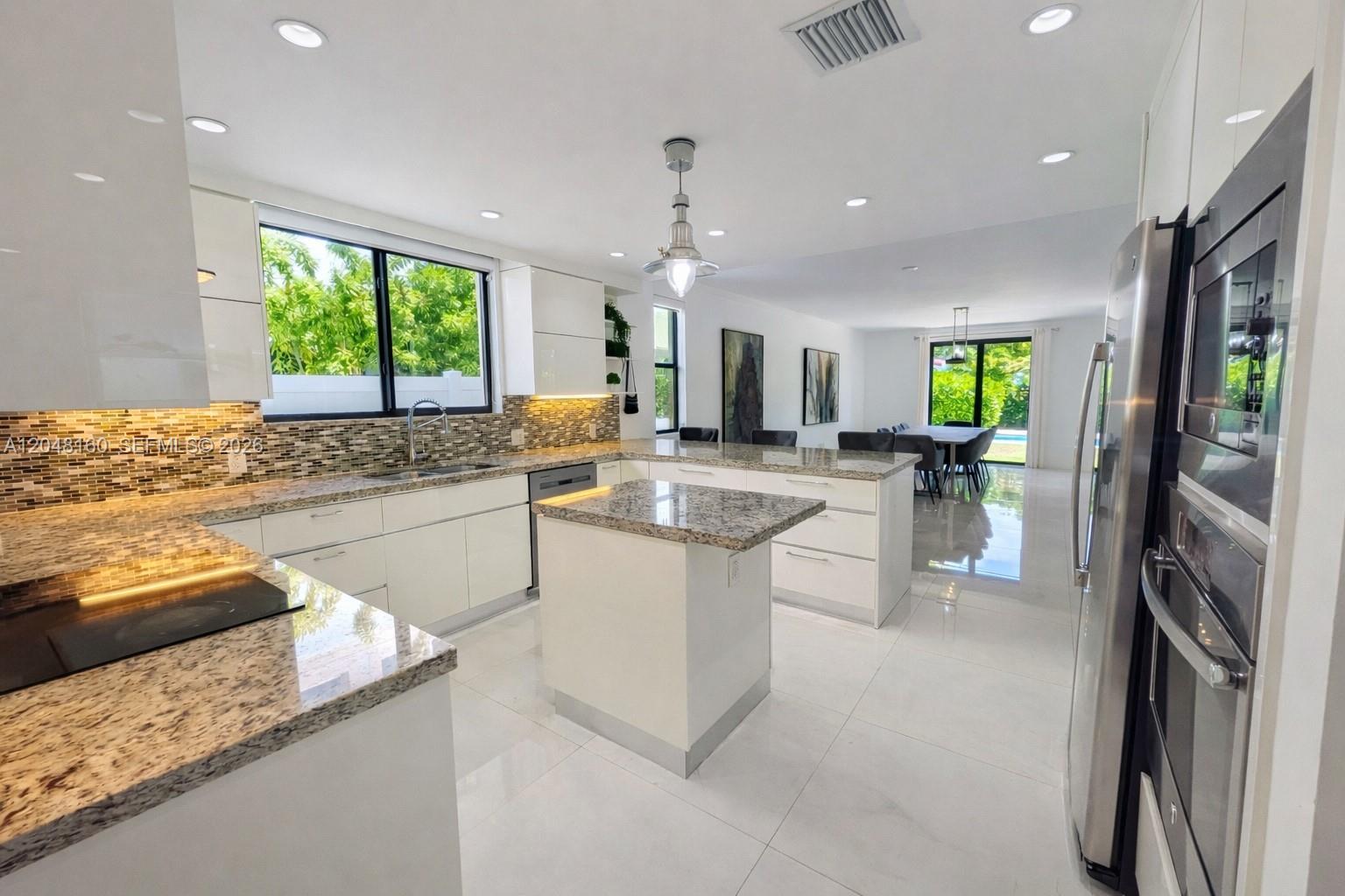 471 Southwest 30th Road Miami, FL 33129 - Photo 9 of 39 elegant modern kitchen with ample counter space, custom cabinetry, glass cooktop and stainless steel appliances.
