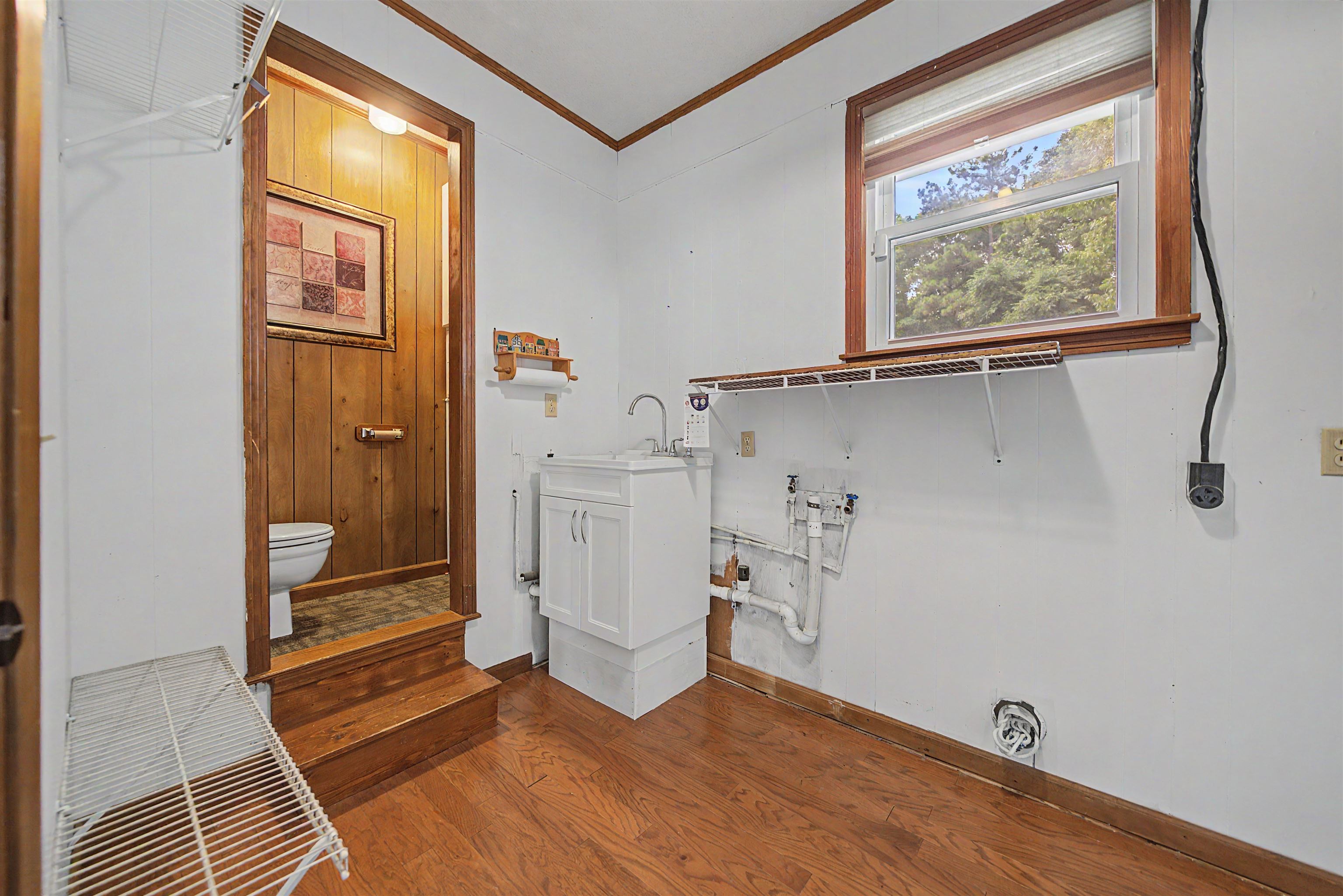 436 Skyline Road Selmer, TN 38375 - Photo 28 of 40 Utility room featuring wood-finish flooring, a single window with wood trim, and a white sink vanity