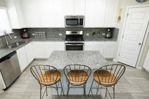 a kitchen with granite countertop a stove a sink and a microwave