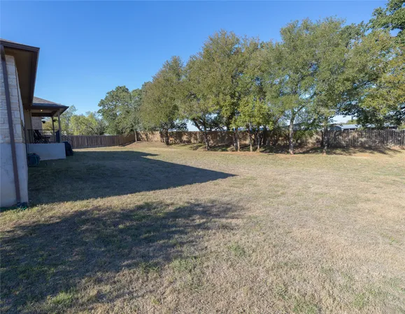 a backyard of a house with table and chairs under an umbrella