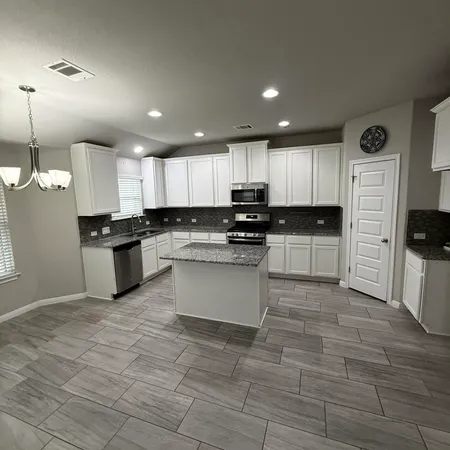 a large kitchen with granite countertop a stove a sink a microwave and a refrigerator