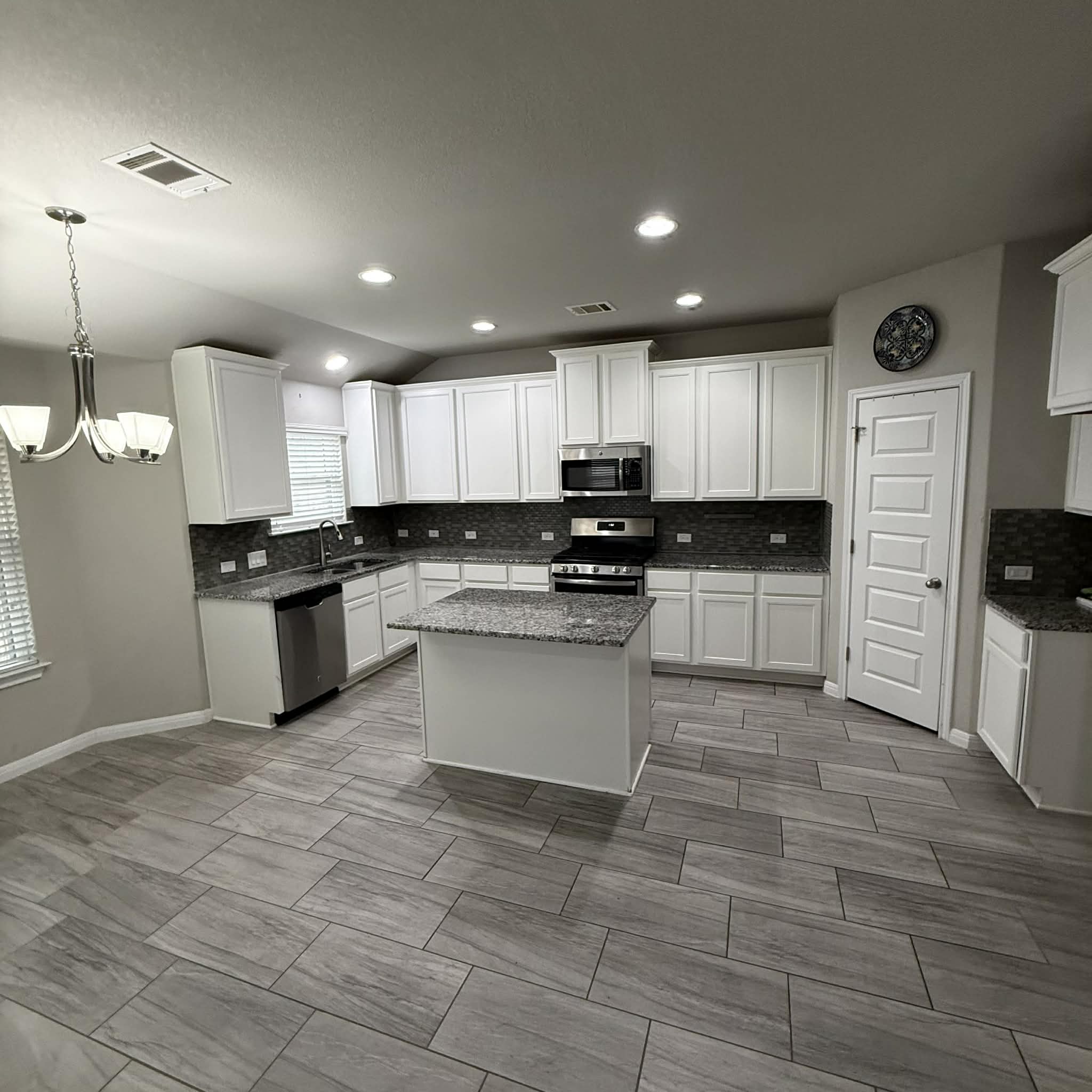 827 Savannah Cove Elgin, TX 78621 - Photo 3 of 31 Kitchen with tasteful backsplash, white cabinets, decorative light fixtures, stainless steel appliances, and lofted ceiling