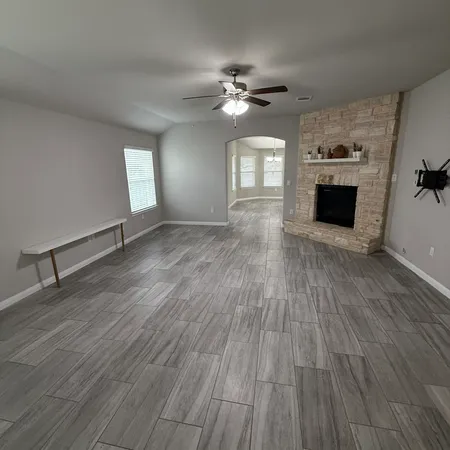 a view of an empty room with wooden floor and a fireplace