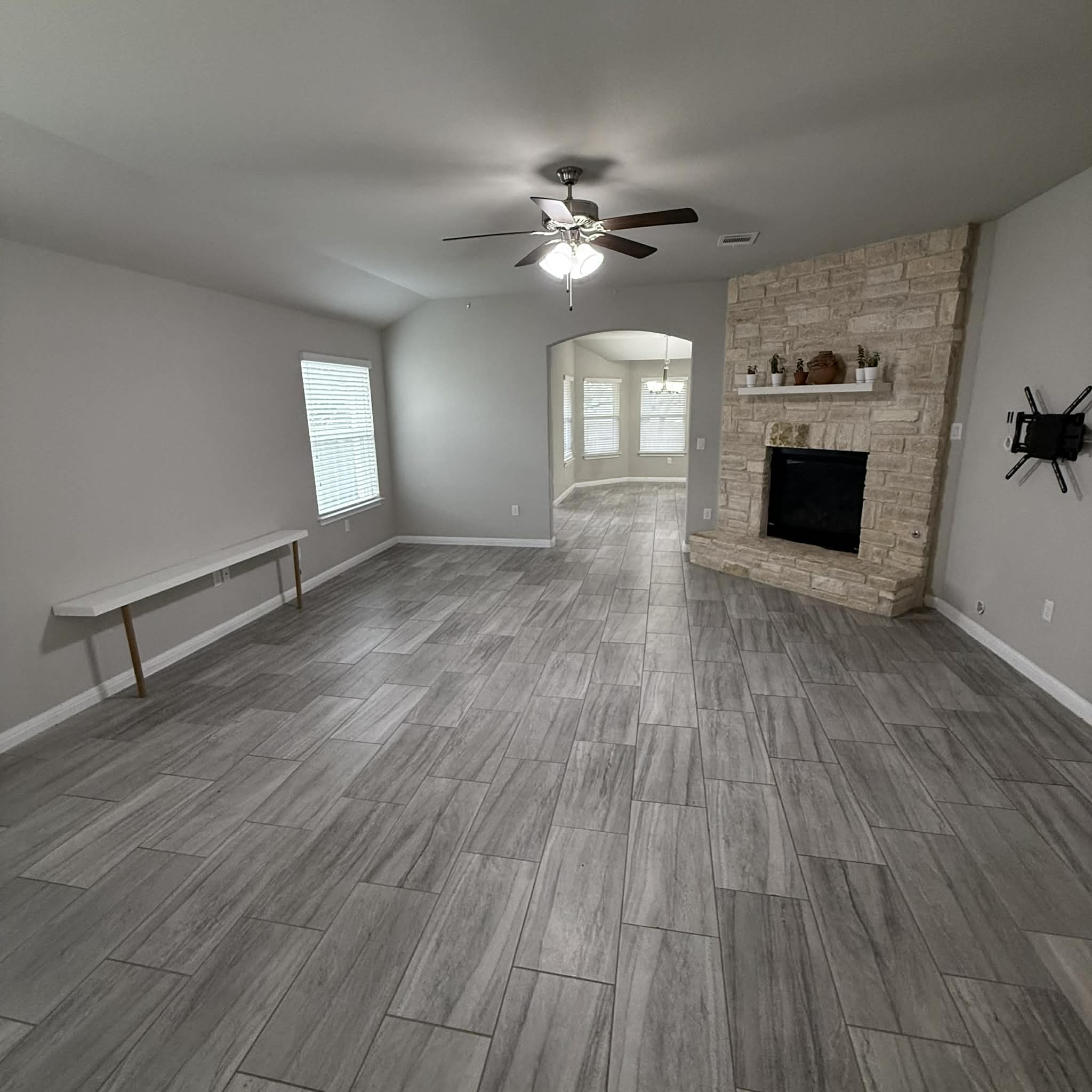 827 Savannah Cove Elgin, TX 78621 - Photo 9 of 31 Unfurnished living room with wood finish floors, arched walkways, a fireplace, and a ceiling fan