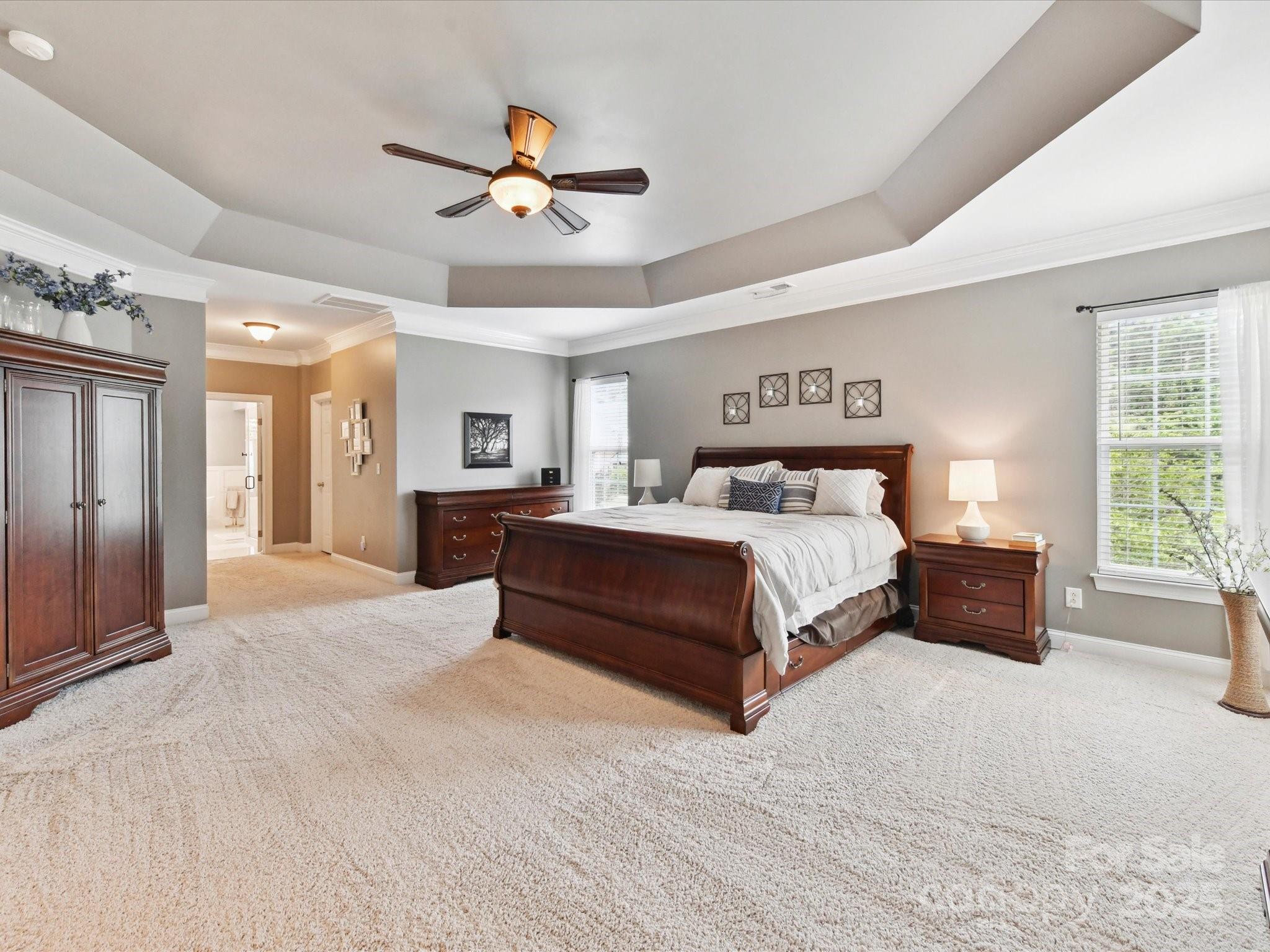 105 Beech Bluff Drive Mount Holly, NC 28120 - Photo 13 of 48 a spacious bedroom with a large bed a chandelier and windows