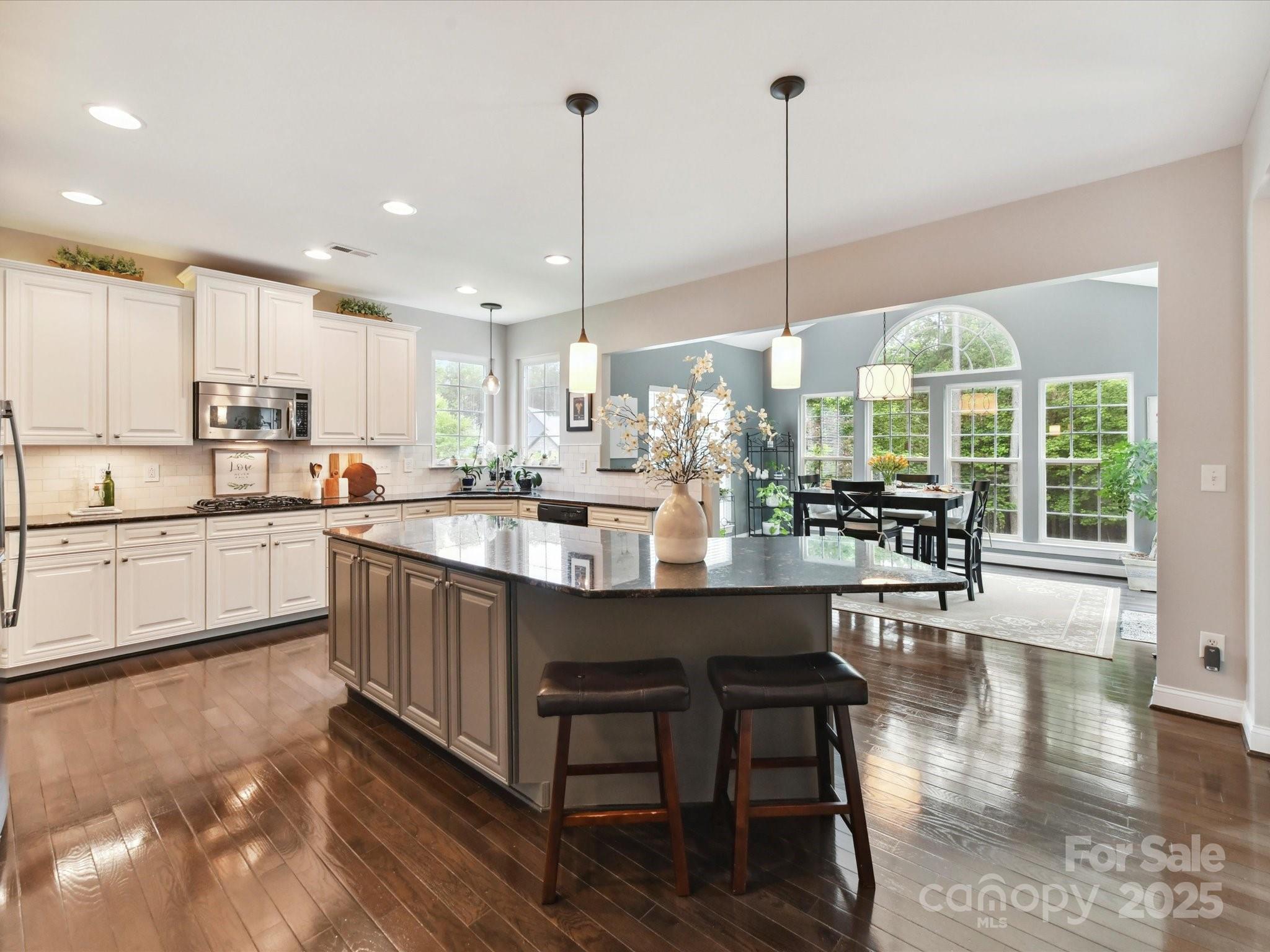 105 Beech Bluff Drive Mount Holly, NC 28120 - Photo 6 of 48 a kitchen with stainless steel appliances granite countertop wooden floor window dining table and chairs