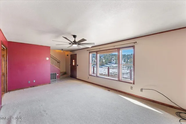 an empty room with chandelier fan and windows