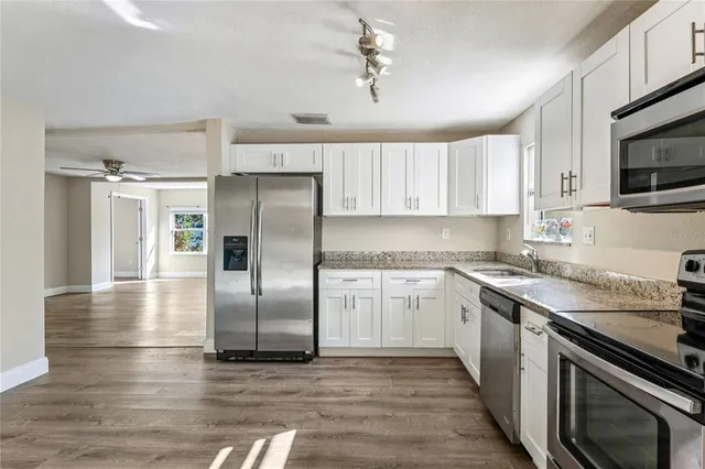 a kitchen with stainless steel appliances granite countertop a refrigerator a stove and a sink