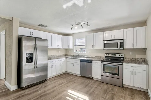 a kitchen with granite countertop white cabinets stainless steel appliances and a counter space