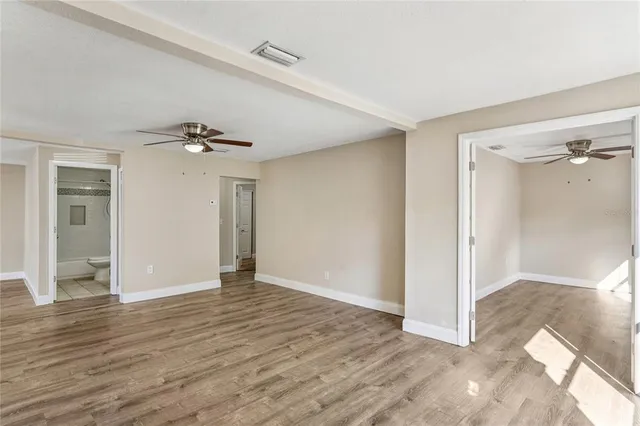 a view of empty room with wooden floor and fan