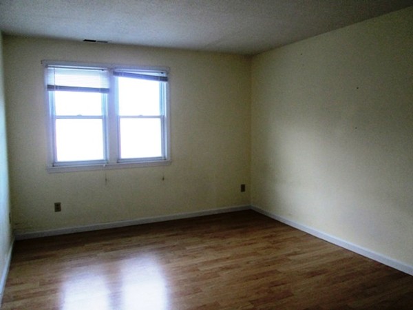 64 Tennis Plaza Road, Unit 2 Dracut, MA 01826 - Photo 5 of 20 an empty room with wooden floor and windows
