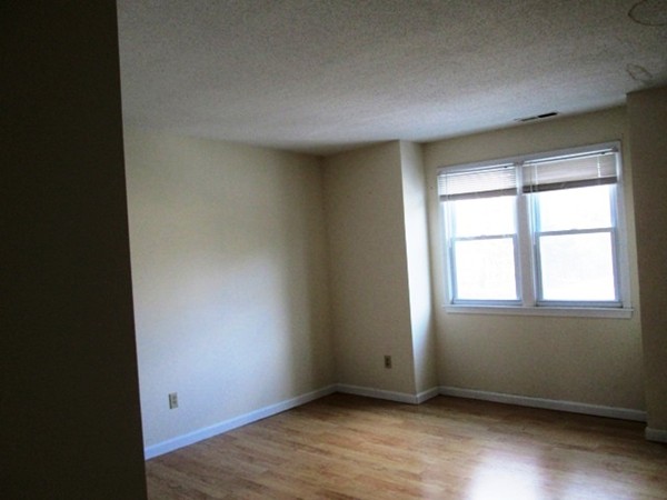 64 Tennis Plaza Road, Unit 2 Dracut, MA 01826 - Photo 8 of 20 an empty room with wooden floor and windows